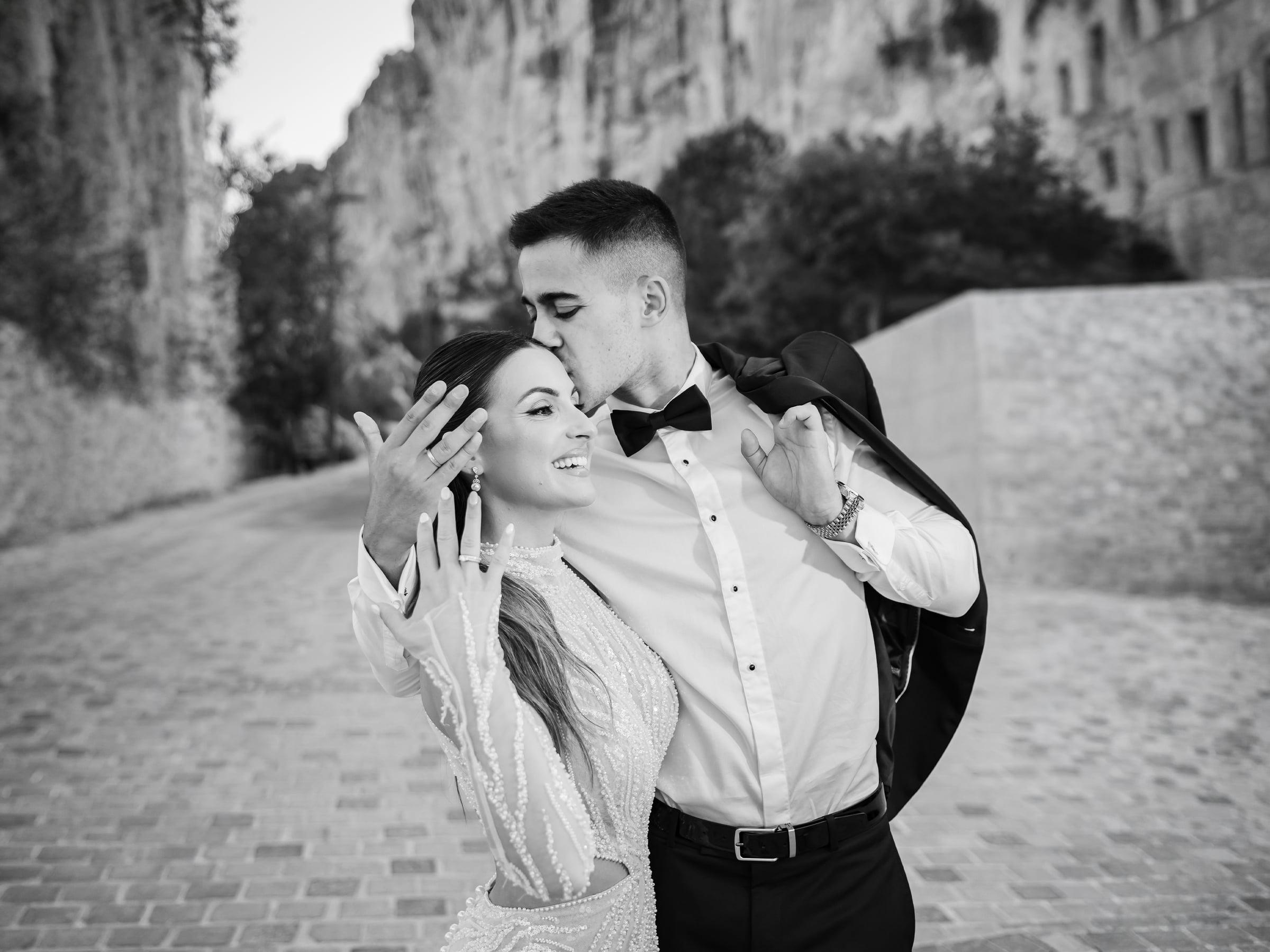 Bride and groom laughing together on a cobblestone street, black and white